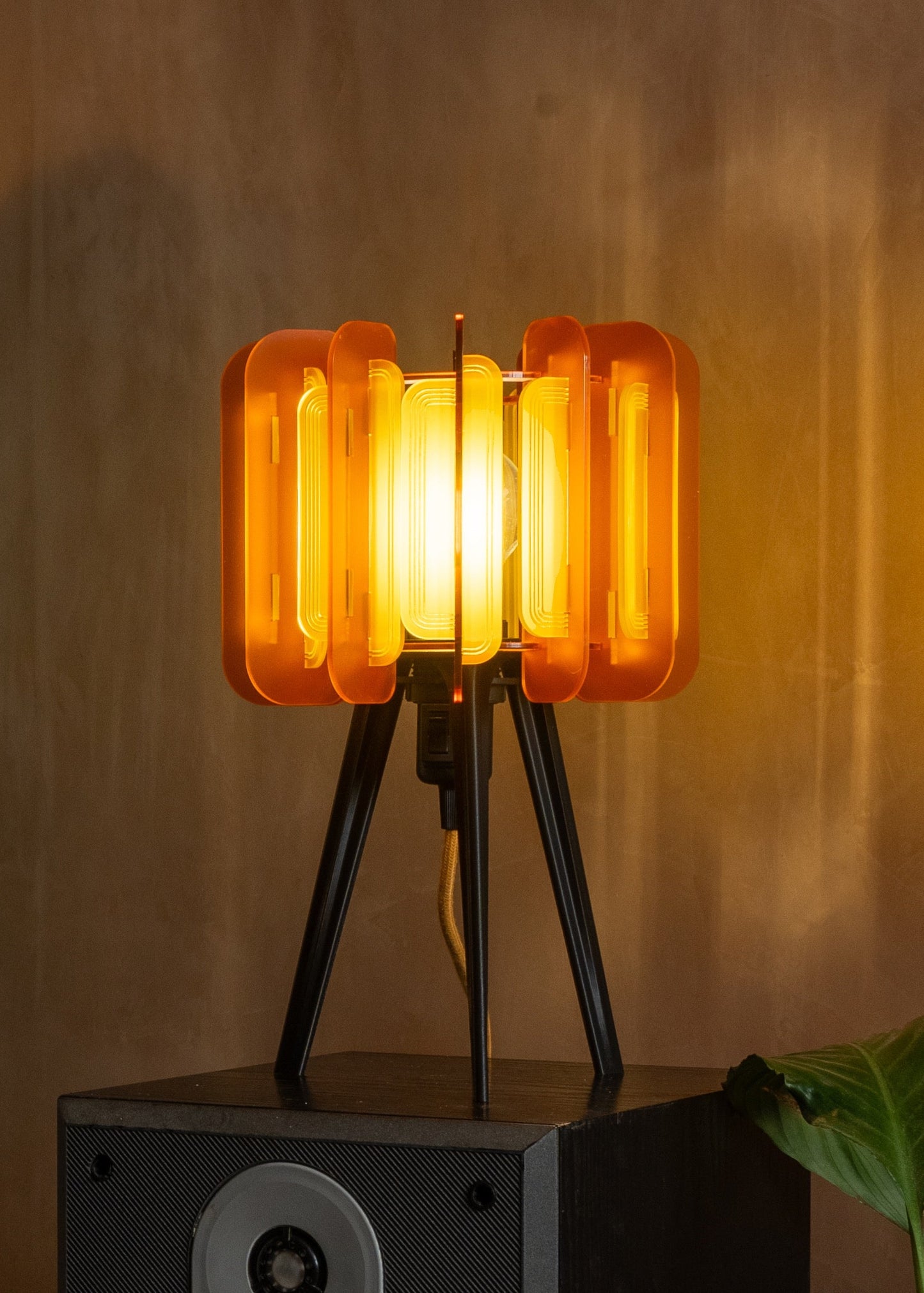 Both Saffron and Burnt Orange Mini Poppy lamps styled with rattan and wood textures. The warm ambient glow and retro palette create a cosy, design-forward corner — ideal for small-space lighting and 1970s home inspiration.