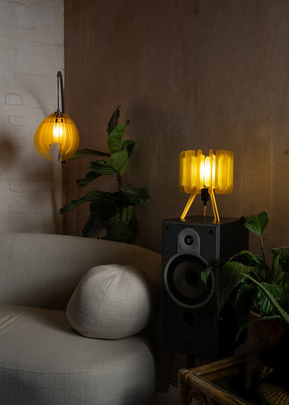 Two-tone yellow Mini Poppy lamp styled with leafy green plants and natural textures. The citrus palette adds a fun, refreshing element to boho, retro, or biophilic interior design.